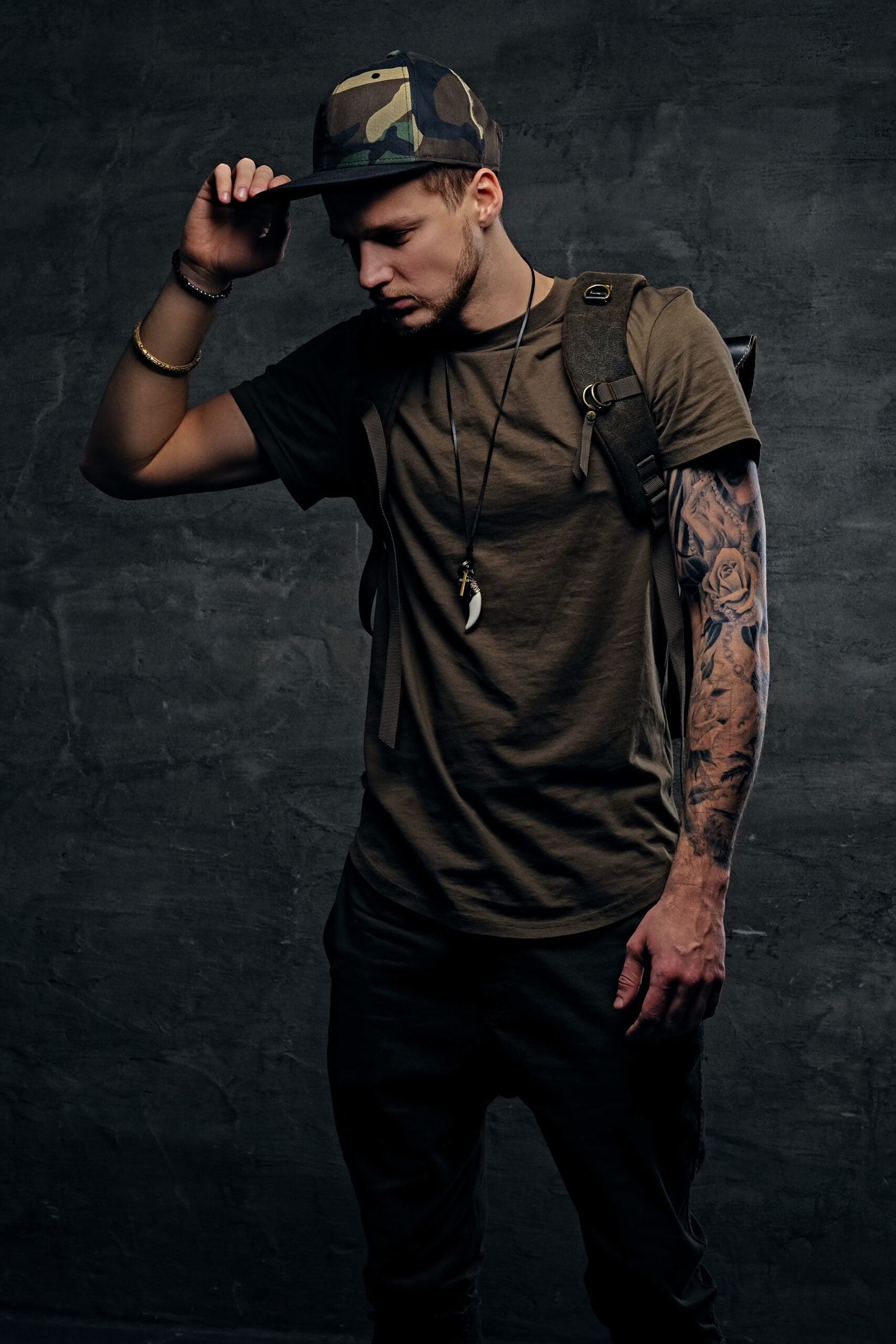 urban-style-backpacker-with-tattooed-arms-dressed-dark-green-t-shirt-camo-cap-scaled.jpg