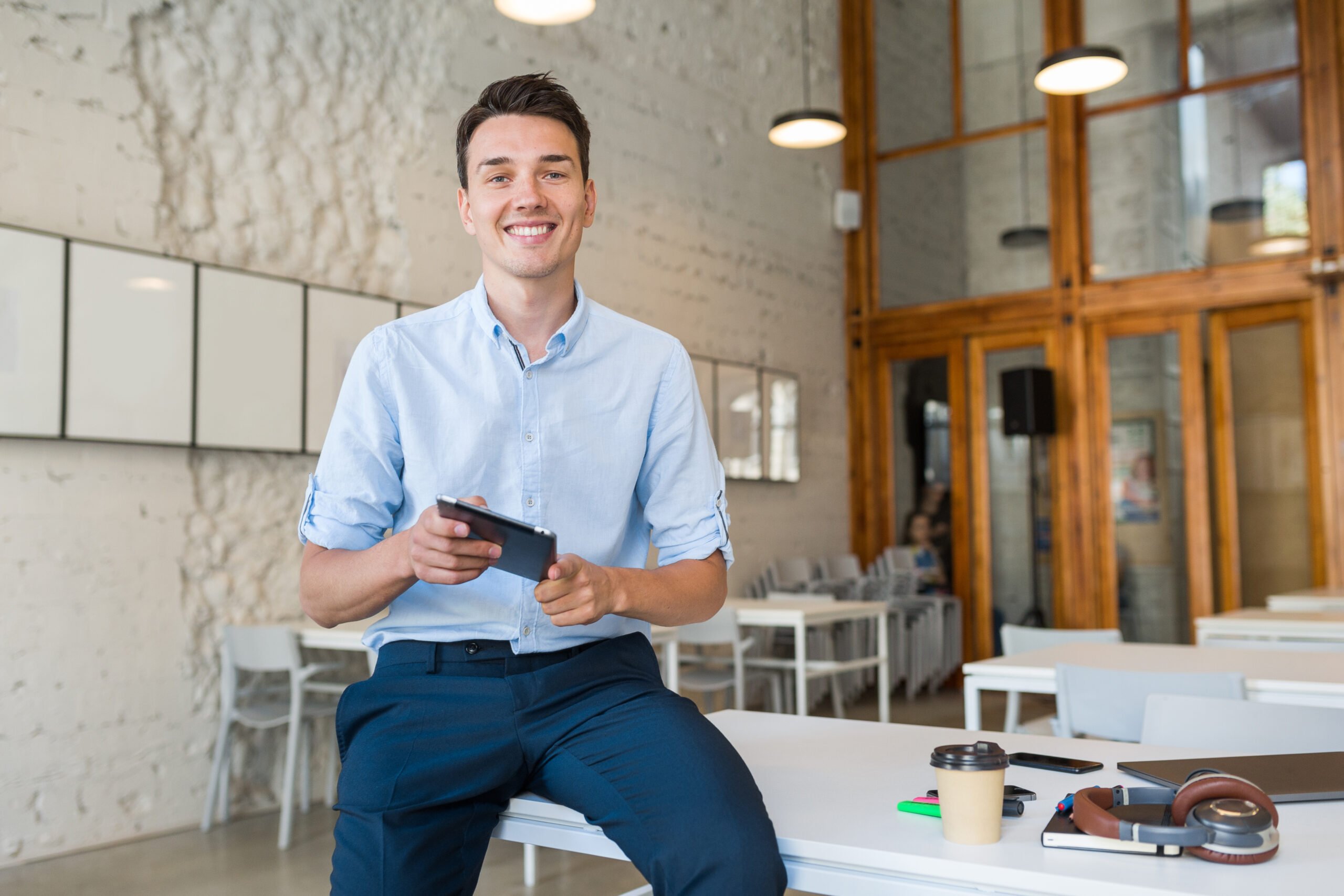 young-stylish-smiling-man-co-working-office-startup-freelancer-holding-using-tablet-scaled.jpg